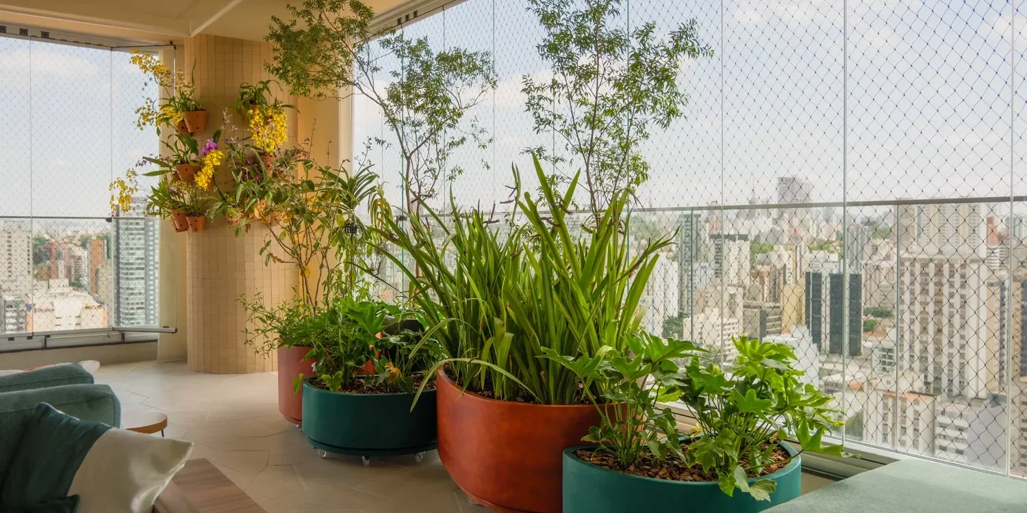 Varanda de apartamento em São Paulo com floreiras e o skyline da cidade ao fundo